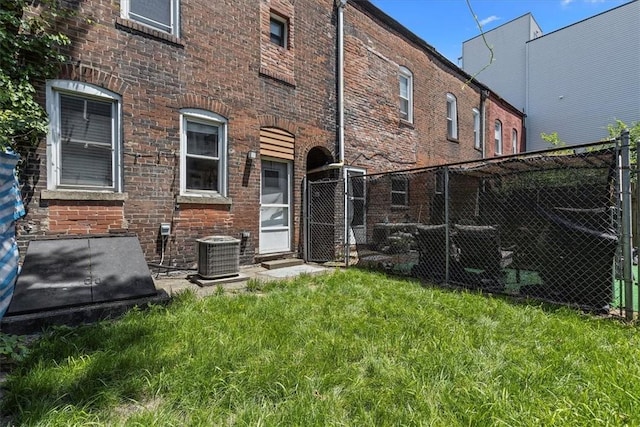 back of property featuring central air condition unit and a yard