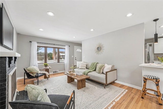 living room with light wood-type flooring and a brick fireplace