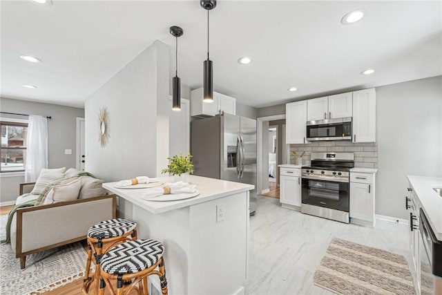 kitchen featuring appliances with stainless steel finishes, hanging light fixtures, white cabinets, and tasteful backsplash