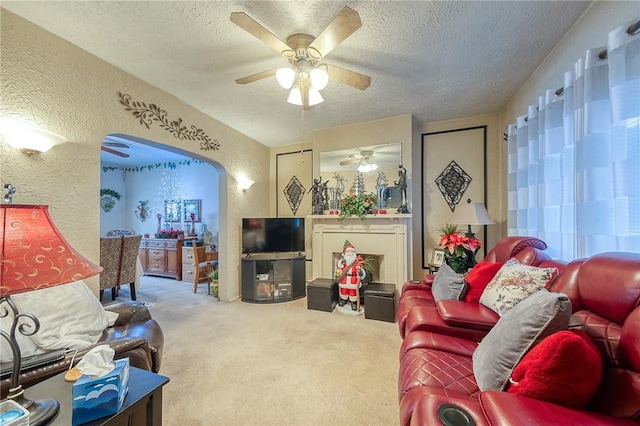 living room featuring a textured ceiling, carpet floors, and ceiling fan