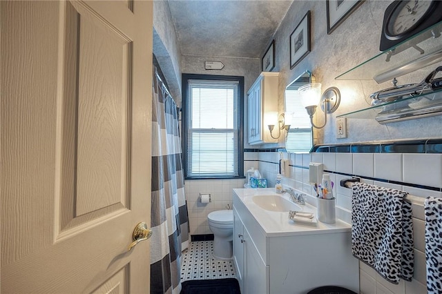 bathroom with tile walls, vanity, toilet, and a shower with shower curtain