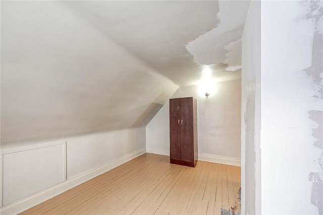 additional living space featuring baseboards, vaulted ceiling, and hardwood / wood-style flooring
