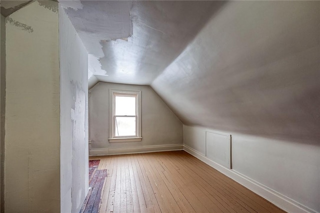 additional living space with wood-type flooring, baseboards, and lofted ceiling
