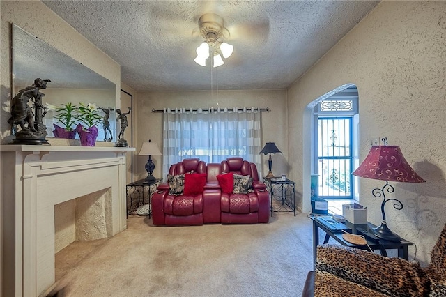 living room with a textured wall, a ceiling fan, and a textured ceiling