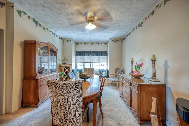 dining room with ceiling fan, a textured ceiling, and light colored carpet