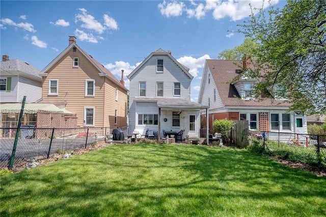 rear view of house featuring a lawn and a fenced backyard