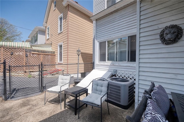 view of patio with fence, cooling unit, and a gate