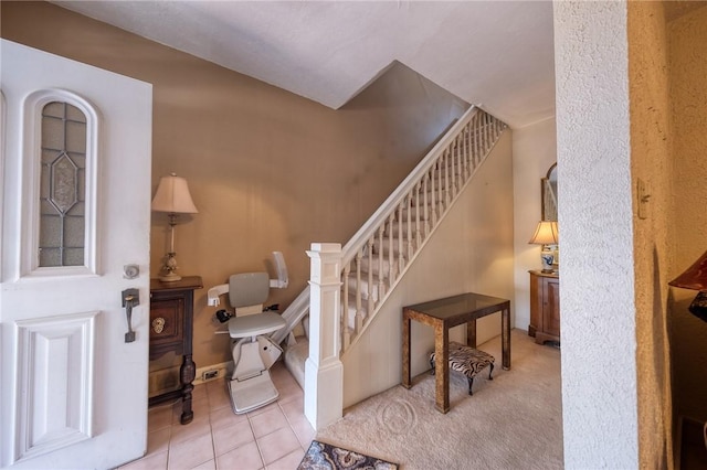 foyer featuring carpet flooring, stairway, and tile patterned flooring
