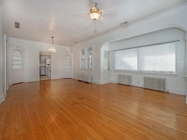 unfurnished living room with ceiling fan with notable chandelier, built in features, and radiator