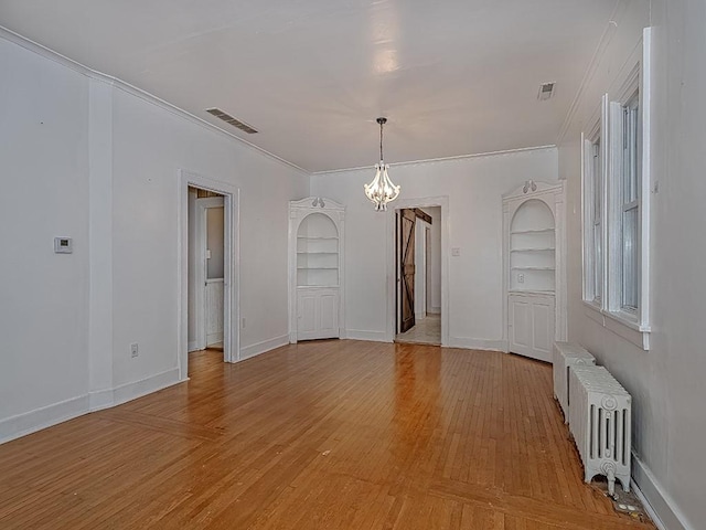 unfurnished dining area featuring a chandelier, light hardwood / wood-style floors, ornamental molding, radiator heating unit, and built in shelves