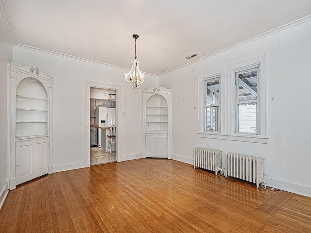 unfurnished dining area featuring ornamental molding, built in features, a notable chandelier, and radiator