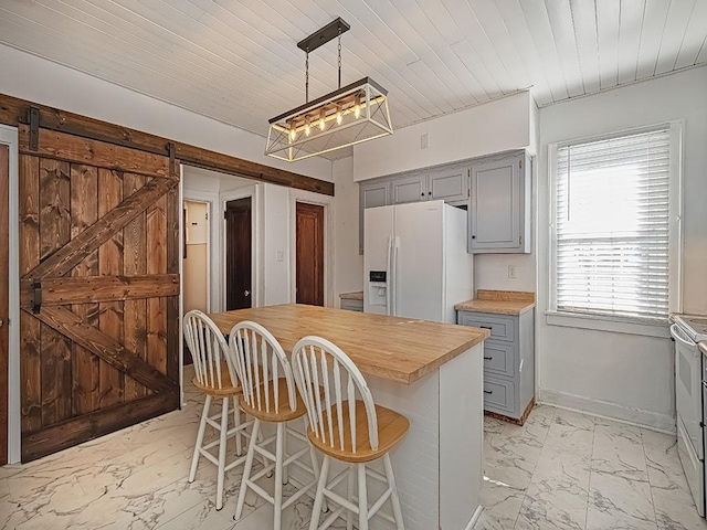 kitchen with white appliances, a barn door, gray cabinetry, hanging light fixtures, and a center island