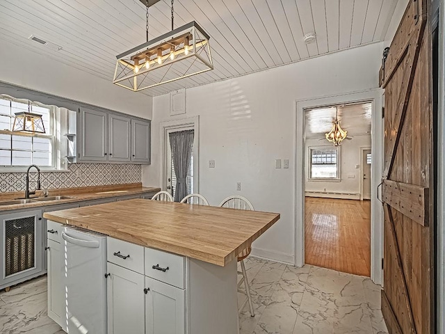 kitchen with butcher block counters, sink, a center island, dishwasher, and a barn door