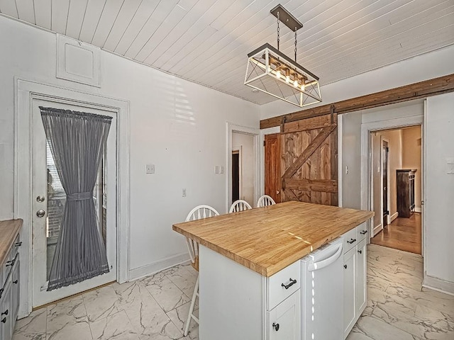 kitchen featuring decorative light fixtures, white cabinets, butcher block counters, and a barn door