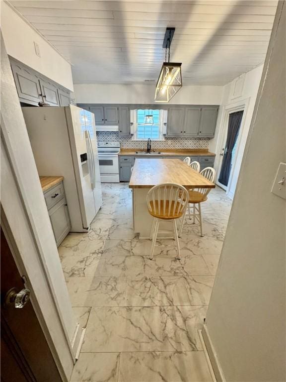 kitchen with white appliances, gray cabinetry, wooden counters, and sink