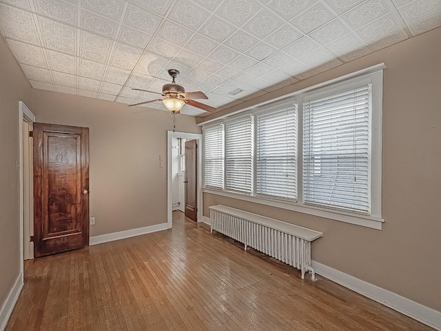 empty room with ceiling fan, radiator, and wood-type flooring