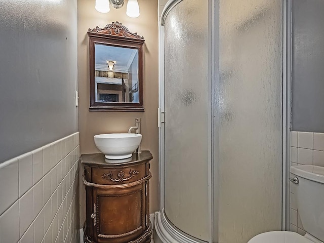 bathroom featuring toilet, a shower with door, vanity, and tile walls