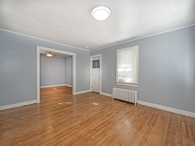 spare room featuring light wood-type flooring, ceiling fan, and radiator