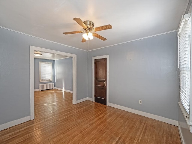 unfurnished room featuring hardwood / wood-style flooring, ceiling fan, radiator, and ornamental molding