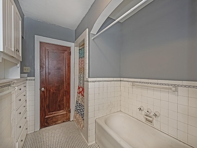 bathroom featuring tile walls and a tub to relax in