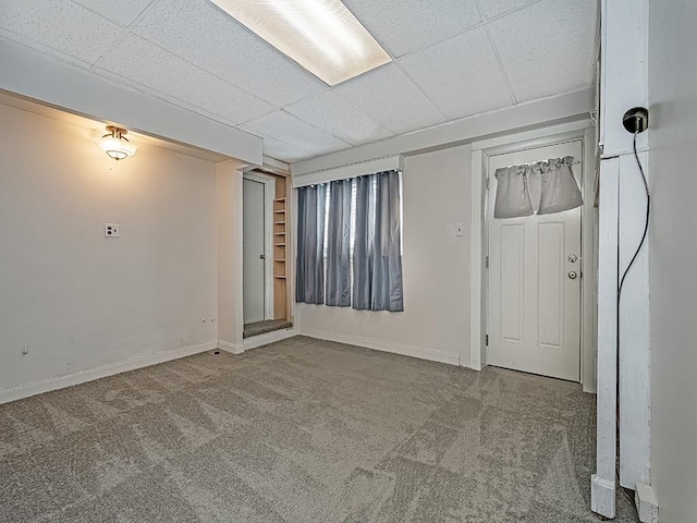 carpeted spare room featuring a drop ceiling