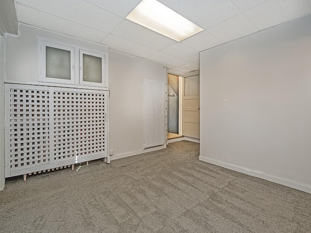 basement featuring a paneled ceiling and light colored carpet