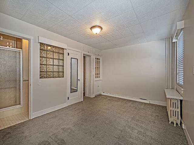 spare room featuring a baseboard heating unit and carpet floors