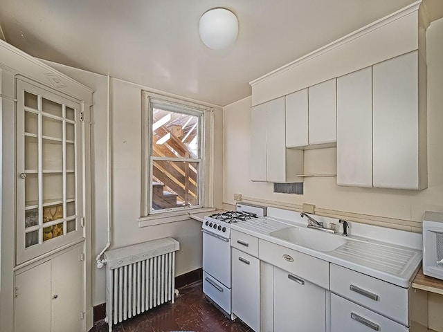 kitchen featuring radiator, white cabinets, white range with gas cooktop, and sink