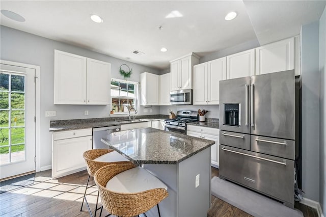 kitchen with appliances with stainless steel finishes, a center island, a breakfast bar, sink, and white cabinetry