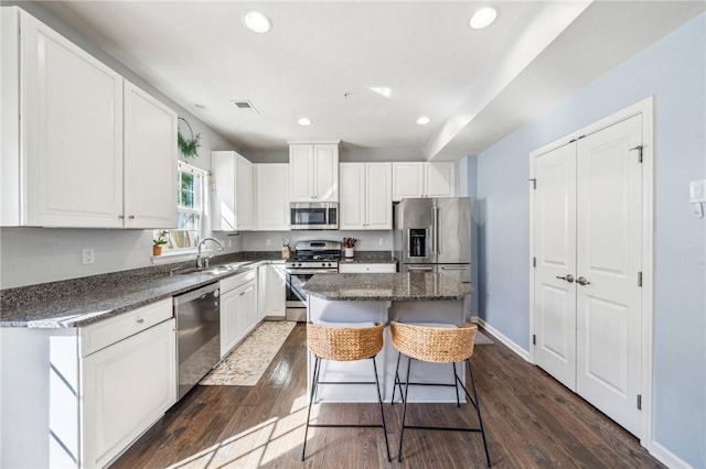 kitchen featuring stainless steel appliances, white cabinets, dark hardwood / wood-style flooring, and a center island