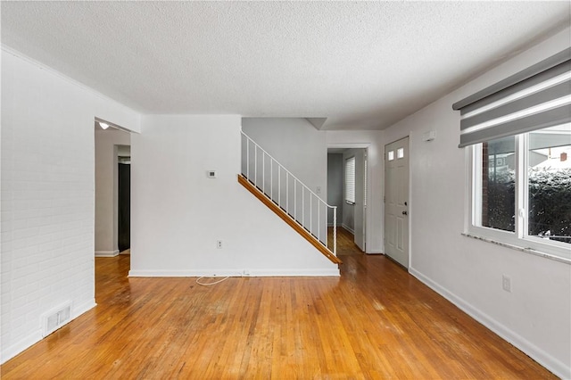 spare room with a textured ceiling and light hardwood / wood-style floors