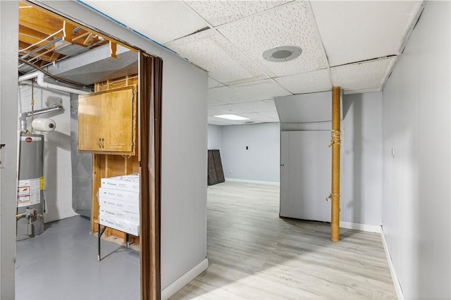 basement featuring water heater and a drop ceiling