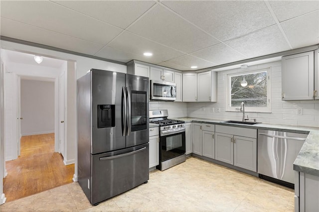 kitchen with sink, a paneled ceiling, gray cabinetry, and appliances with stainless steel finishes