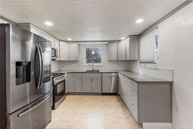 kitchen with gray cabinets, backsplash, dark stone counters, appliances with stainless steel finishes, and sink