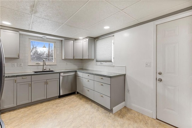 kitchen featuring gray cabinetry, decorative backsplash, a drop ceiling, sink, and stainless steel dishwasher