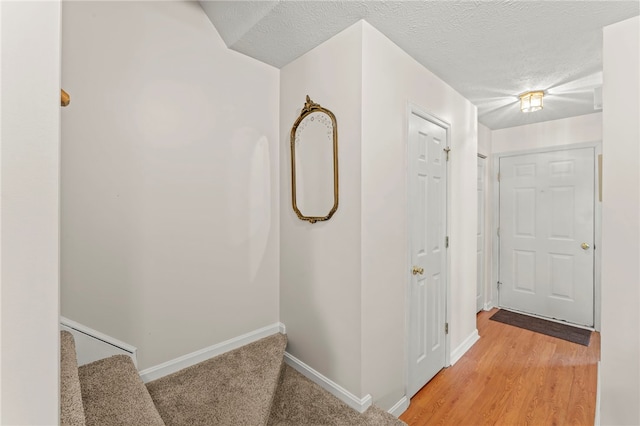 corridor with a textured ceiling and light wood-type flooring