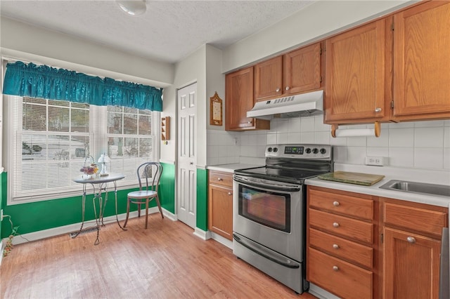 kitchen featuring a textured ceiling, light hardwood / wood-style floors, backsplash, and stainless steel range with electric stovetop