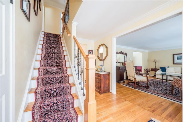 stairway with hardwood / wood-style flooring and ornamental molding