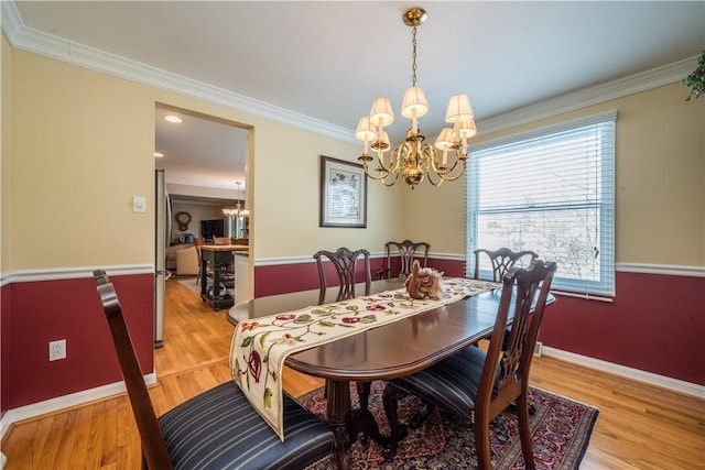 dining space with ornamental molding, light hardwood / wood-style flooring, and a chandelier