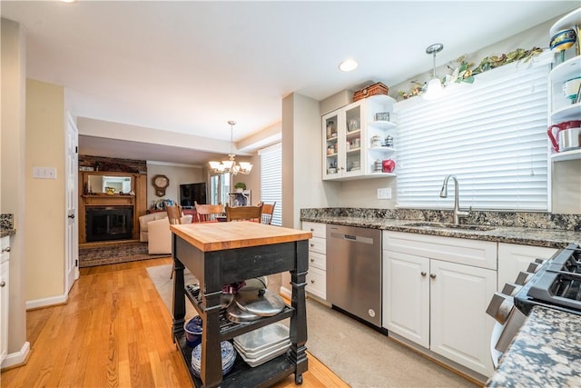 kitchen with appliances with stainless steel finishes, light stone countertops, pendant lighting, white cabinets, and sink