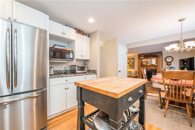 kitchen with stainless steel refrigerator, light hardwood / wood-style floors, hanging light fixtures, white cabinetry, and an inviting chandelier