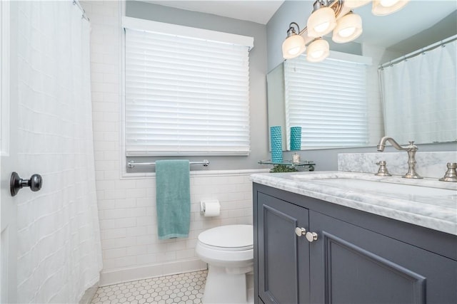 bathroom with tile walls, tile patterned flooring, toilet, and vanity