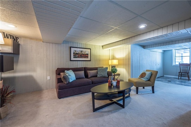 carpeted living room featuring wooden walls