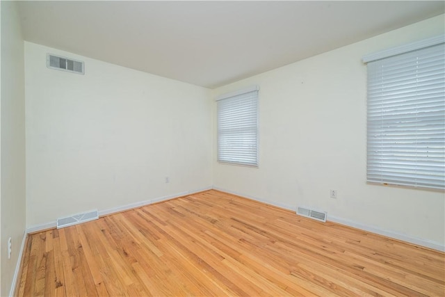 unfurnished room with visible vents, baseboards, and wood finished floors