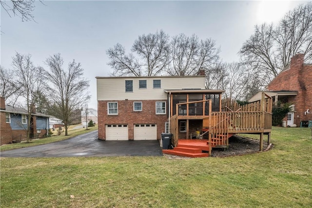 back of property with brick siding, a chimney, an attached garage, a sunroom, and driveway