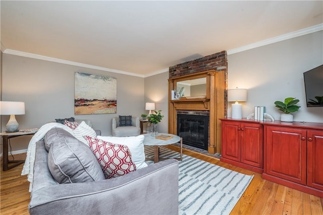 living room with light wood-type flooring, a fireplace, and crown molding