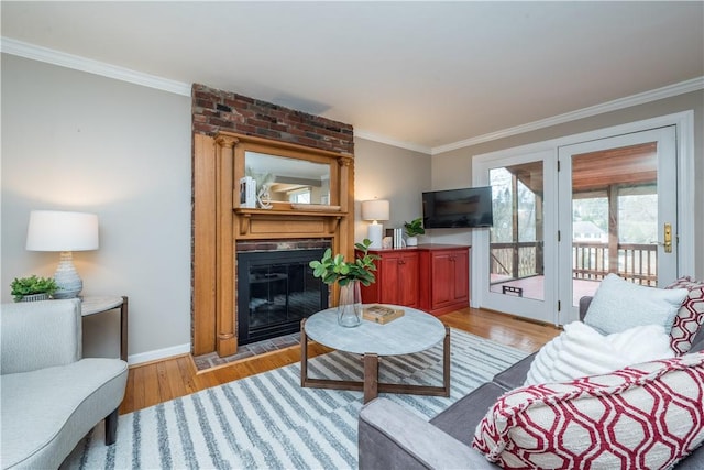 living room with light wood finished floors, a fireplace, and ornamental molding