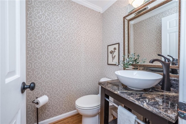 half bath with crown molding, toilet, vanity, baseboards, and wallpapered walls