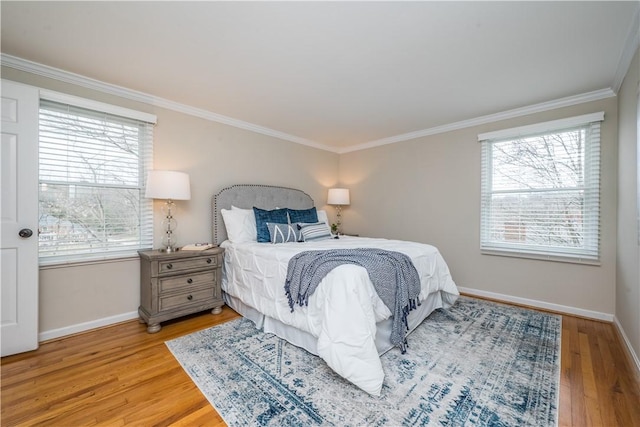 bedroom featuring ornamental molding, multiple windows, and light wood-style floors