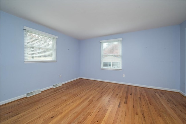 unfurnished room featuring light wood-style flooring, visible vents, and baseboards